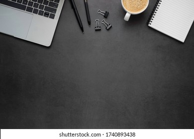 Workplace office with dark grey desk. Top view from above of Laptop, Empty open notebook with pens and coffee. Flat lay, Business-finance or education concept with copy space.
