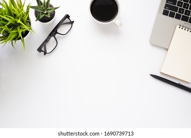 Workplace In Office With White Desk. Top View From Above Of Laptop With Notepad And Coffee. Space For Modern Creative Work Of Designer. Flat Lay With Blank Copy Space. Business And Finance Concept.