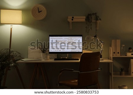Workplace of programmer with modern computer and glowing lamps at evening in office