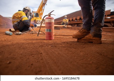 Workplace Safety Precaution Stand By Fire Wash Foots Standing 1.5 M Social Distancing Avoiding Coronavirus -19 With Fire Extinguisher In Reach While Defocused Co Worker Conducting Welding Background  