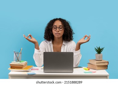 Workplace Stress Management. Calm Young Black Woman Meditating In Front Of Laptop On Blue Background, Copy Space. Millennial Female Student Feeling Peaceful And Balanced, Practicing Yoga At Work