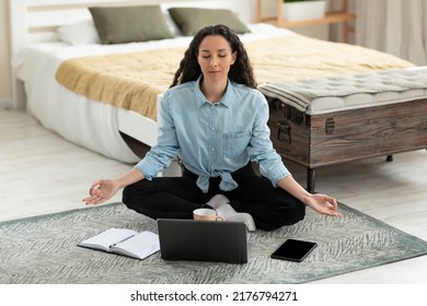Workplace Stress Management. Calm Young Woman Meditating With Closed Eyes In Front Of Laptop Pc At Home, Full Length. Young Female Freelancer Feeling Peaceful And Balanced, Doing Yoga In Bedroom