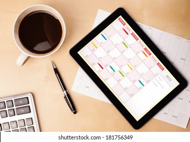 Workplace With Tablet Pc Showing Calendar And A Cup Of Coffee On A Wooden Work Table Close-up