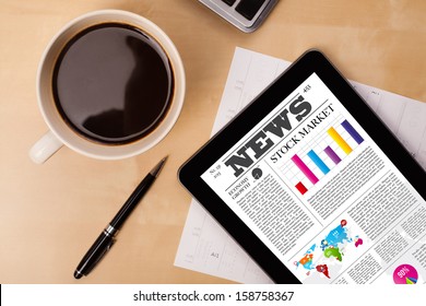 Workplace with tablet pc showing latest news and a cup of coffee on a wooden work table close-up - Powered by Shutterstock