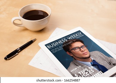 Workplace With Tablet Pc Showing Magazine Cover And A Cup Of Coffee On A Wooden Work Table Close-up