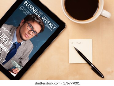 Workplace With Tablet Pc Showing Magazine Cover And A Cup Of Coffee On A Wooden Work Table Close-up