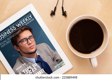 Workplace With Tablet Pc Showing Magazine Cover And A Cup Of Coffee On A Wooden Work Table Close-up