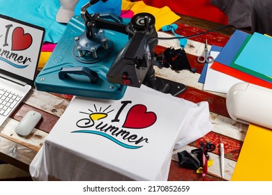 Workplace top view with heat transfer shirt press to manufacture custom DIY design shirts with notebook computer and cutting machine. Startup fashion designer production concept. - Shutterstock ID 2170852659