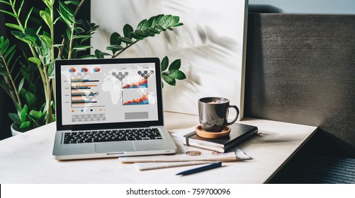 Workplace without people, close-up of laptop with graphs, charts, diagrams on screen on white table, desk.Nearby is closed paper notebook, pen, newspaper, cup of coffee. Online marketing, e-commerce. - Powered by Shutterstock