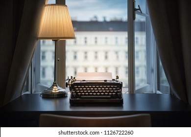 Workplace of a writer, journalist, creator. An old typewriter and a lamp on the table. Retro style. The concept on scientific, historical, literature, education and philosophical topics. 
