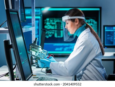 Workplace of young woman in modern microelectronics manufacturing lab. Engineer works in a modern scientific laboratory on computing systems and microprocessors.