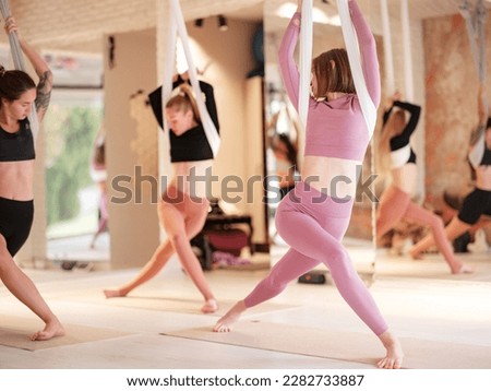workshop of air yoga and stretching in yoga studio. women practices different inversion antigravity yoga with hammock. balance between mental and physical, one person effort and achievement concept