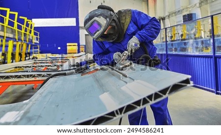 Workshop for assembling metal frames for subway cars, trams and trains. Welders assemble body parts.