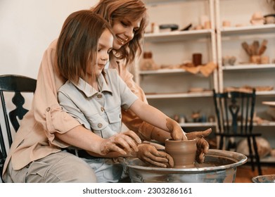 In the workshop. Mother with little girl making ceramic pot. - Powered by Shutterstock