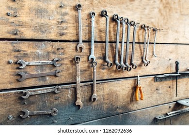 Workshop scene. Old tools hanging on wall in workshop. Vintage retro garage style. Old wrenches hanging wall in old garage.