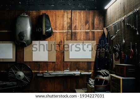 Workshop scene. Old tools hanging on wall in workshop, Tool shelf against a table and wall, vintage garage style, with blank paper