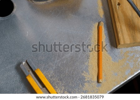 Workshop table with carpenter pencil, utility knife, wood piece and sawdust