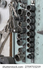 A workshop wall displays organized socket sets on metal rails with visible size markings, alongside locking pliers, captured in selective focus, 2026