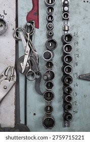 A workshop wall displays organized socket sets on metal rails with visible size markings, alongside locking pliers, captured in selective focus, 2026