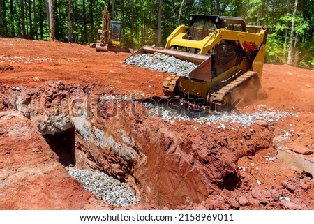 Worksite oconstruction area with loader small bulldozer moving the stone gravel