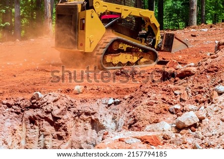 Worksite outdoors with loader small bulldozer moving breakstone at construction area.