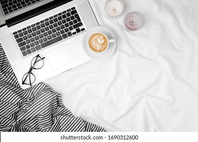 Workspace in bed with laptop and coffee. Morning concept. Flat lay 