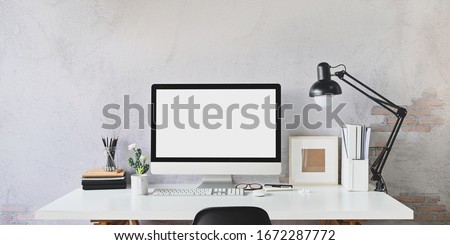 Workspace blank screen Computer and Equipment on table and loft wall background.