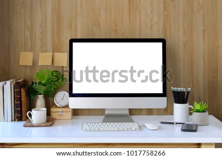 Workspace and blank screen desktop computer.Mockup desktop computer, coffee mug, plant and home office accessories on white desk.