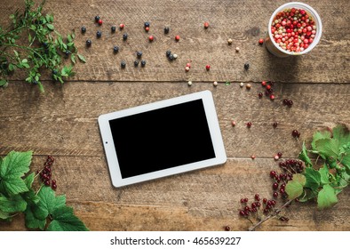 Workspace. Composition with tablet pc and bilberries, cowberries, red currant with leaves in the old wooden impressive boards. Natural light shadows. Freelance concept.