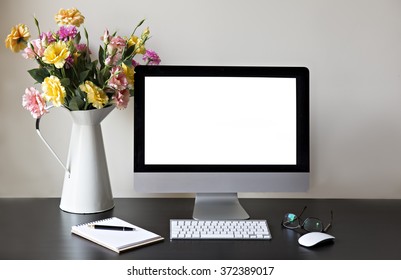 Workspace with computer at home or in the studio , a desk with flowers.