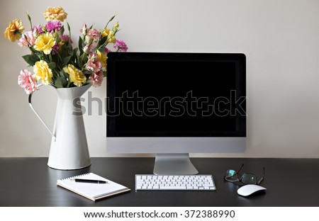 Workspace with computer at home or in the studio , a desk with flowers.