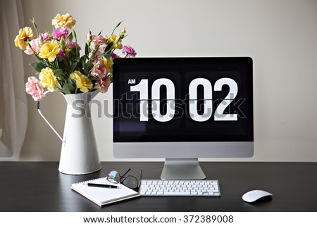 Workspace with computer at home or in the studio , a desk with flowers.