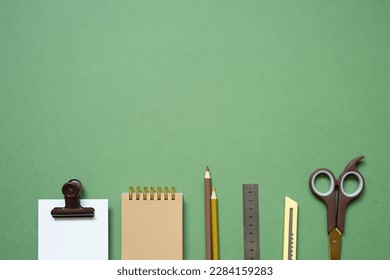 ワークスペースの概念。緑の机の上にメモ帳と筆記用具。フラットレイ、トップビュー、コピー用スペースの写真素材