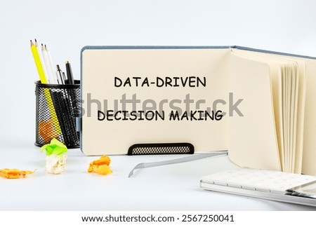 A workspace displaying a notebook opened to the page titled data-driven decision making. Surrounding items include pens, a holder, and colorful paper scraps, indicating creativity and organization.