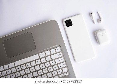 Workspace Essentials Phone Laptop and Earphones on white desk. The sleek design of the gadgets against the clean backdrop creates an atmosphere of modern professionalism. - Powered by Shutterstock