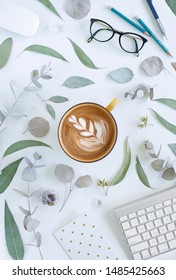 Workspace With Eucalyptus Leaf Border, Green Leaves With Latte, Flat Lay Border On White Background With Office Items Keyboard, Notecard, Glasses, Mouse, Pencils, Latte Art