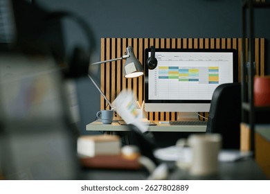 Workspace featuring organized computer setup with wooden paneling background for home office space. Desk lamp adding a touch of modernity for productive work environment
