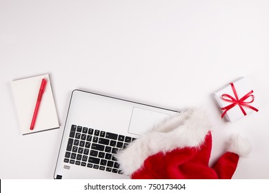 Workspace With Laptop And Christmas Gift And Santa Hat On White Background Flat Lay, Top View, Copy Space.  Business Christmas Holidays Concept, Holiday Online Shopping