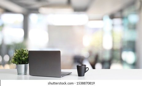 Workspace Laptop Computer And Coffee Cup With Plant Pot On Office Table.