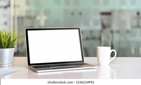 Workspace With Laptop Computer, Coffee Mug And Plant Pot.