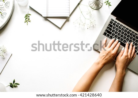 Workspace with laptop, girl's hands, notebook, sketchbook, white vintage tray, candlesticks on white background. Flat lay, top view office table desk. Freelancer working place