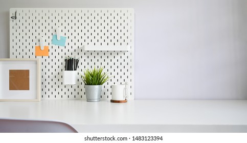 Workspace Office Supply And Pegboard On White Table Copy Space.