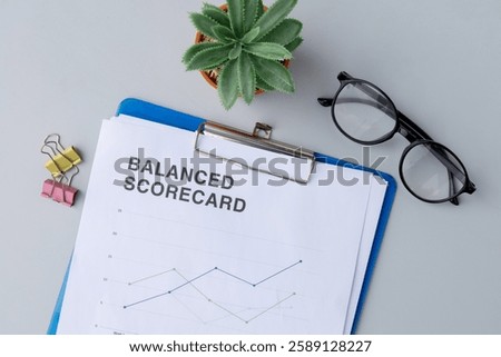 A workspace setting showcasing a clipboard with a balanced scorecard paper, representing key performance indicators and corporate strategy.