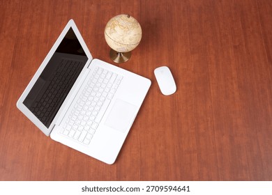 Workspace setup with laptop, globe, and mouse on wooden desk showing organized study environment