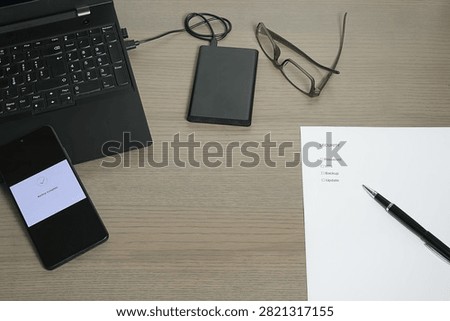 Workspace setup with a laptop, smartphone, external HDD, and a checklist for 