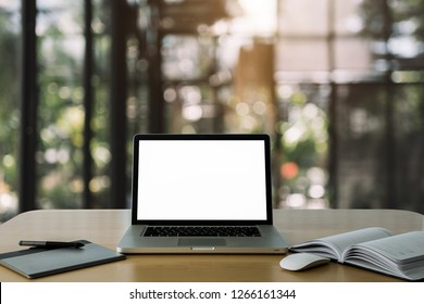Workspace wooden desk with Mockup Laptop with blank screen and wireless mouse and graphics tablet and notebook in office blurred background of bokeh.