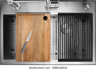 Workstation kitchen sink with a knife placed on a cutting board on top of it