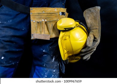Workwear for production workers. A construction worker holding protective accessories. Black background.