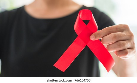 World Aids Day And National HIV/AIDS And Aging Awareness Month Concept With Red Satin Ribbon On Woman's Hand Support