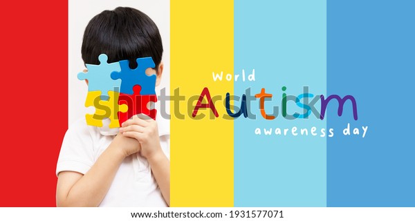 World autism awareness day April 2 - Studio\
Portrait of a cute asian boy cover his face with the colorful\
puzzles pieces. Autism Spectrum Disorder concept, ASD, Syndrome,\
Light it up blue,\
Backdrop.